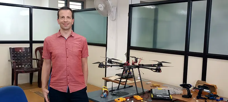 A visitor beside a Nexospark hexacopter in the lab